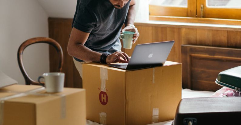 Real Estate Investment - Ethnic man typing on laptop while preparing to relocate