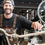 Small Business - Happily Smiling Man Standing Near Gray Bars