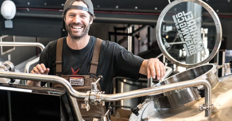 Small Business - Happily Smiling Man Standing Near Gray Bars