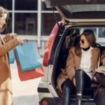 Merger Acquisition - Young woman demonstrating shopping bags to friends