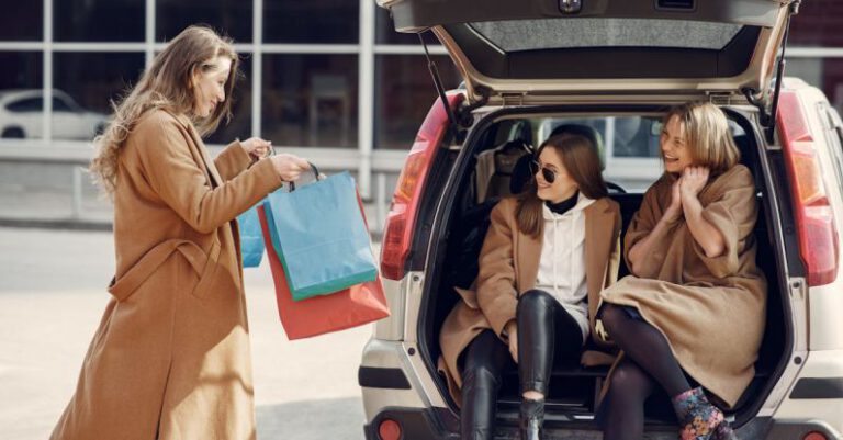 Merger Acquisition - Young woman demonstrating shopping bags to friends