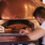 AI Finance - A man is working on a pizza oven in a restaurant