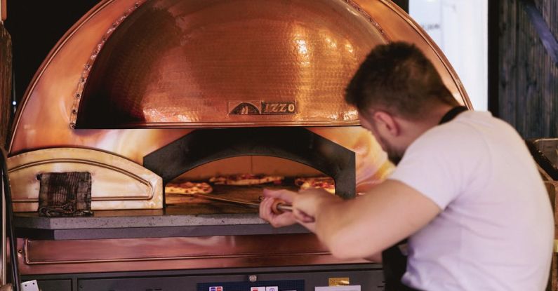 AI Finance - A man is working on a pizza oven in a restaurant