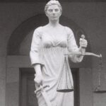 Antitrust Law - A statue of a woman holding a scale in front of a building