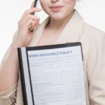 Insurance Policy - A Woman in Beige Blazer Holding a Document while Having a Phone Call