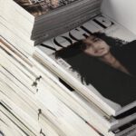 E-commerce Trend - High angle many fashion magazines stacked on floor against white brick wall in studio