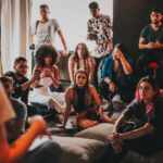 Compound Interest - Group of multiethnic people gathering around female speaker in studio