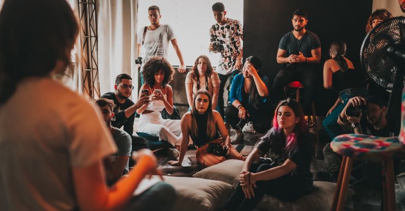 Compound Interest - Group of multiethnic people gathering around female speaker in studio