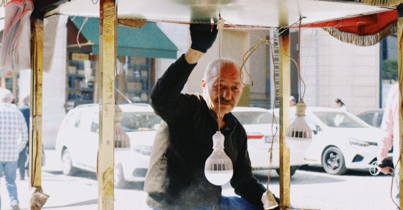 Market Cycles - Elderly Seller of Street Food Standing by Stall