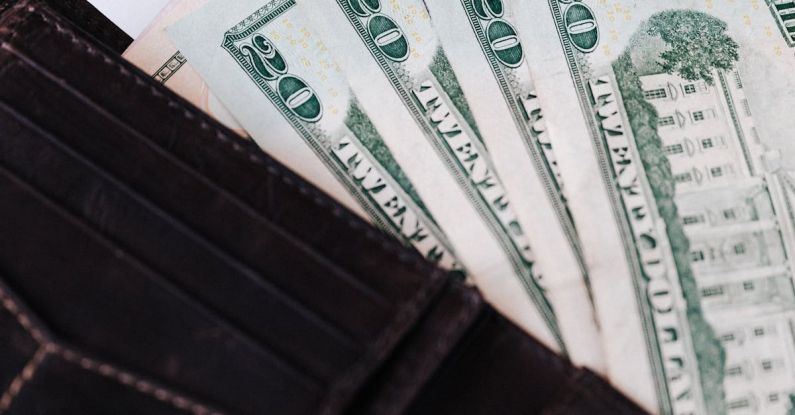 Debt Market - From above of black leather wallet with cash money of twenty dollars placed on white table