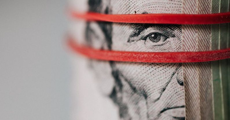 Trade Tensions - Closeup of rolled United States five dollar bills tightened with red rubber band