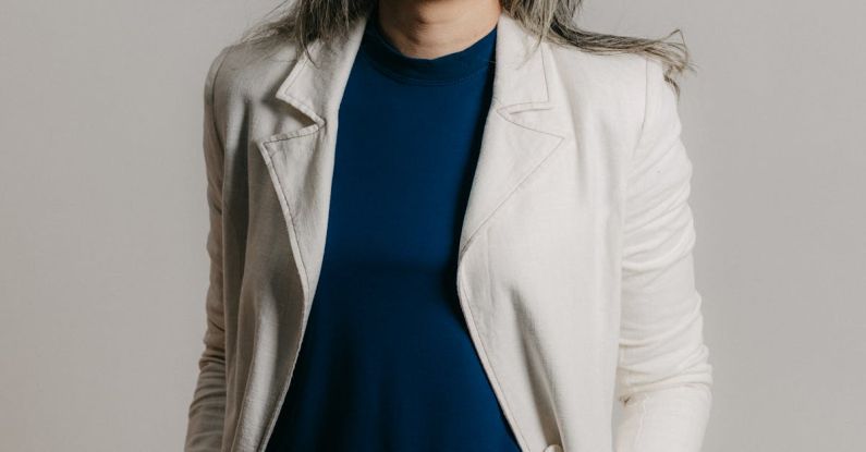 Corporate Sustainability - A woman in a white blazer and blue top smiling